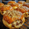Golden-brown garlic parmesan cheeseburger bombs with melted cheese and beef filling, topped with herbs and seasoning.