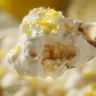 Close-up of creamy lemon mascarpone tiramisu layers with lemon zest and soaked ladyfingers on a spoon.