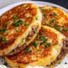 Golden mashed potato pancakes filled with seasoned ground beef, garnished with chopped parsley.