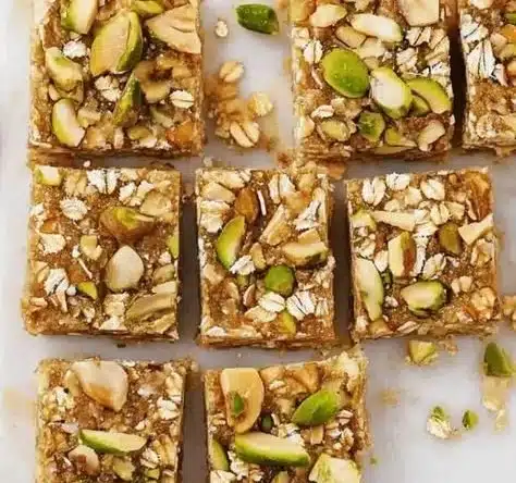 Healthy pistachio oat squares with nuts and oats on a wooden table