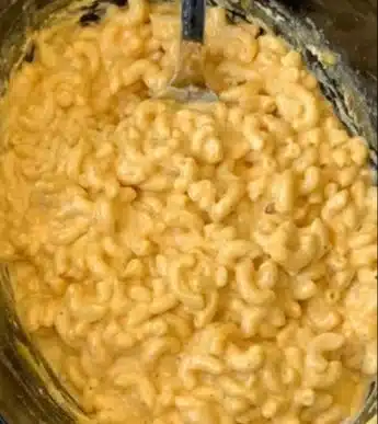 Delicious homemade mac and cheese in a cheesy casserole dish on a rustic table.