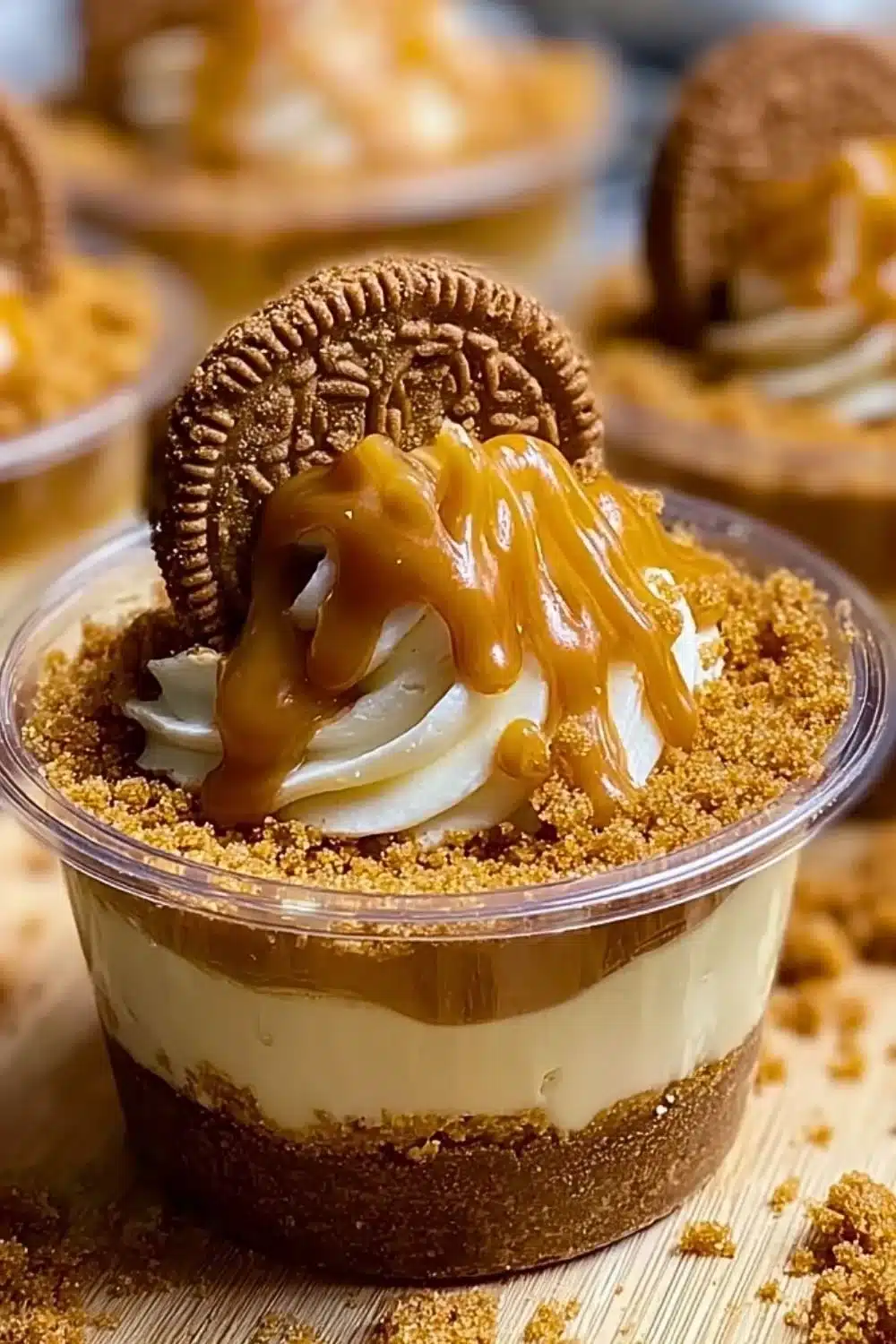 Delicious Cookie Butter Cheesecake Cups topped with cookie crumbs and drizzled with sauce.