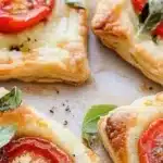 Delicious baked tomato tarts topped with herbs and cheese on puff pastry