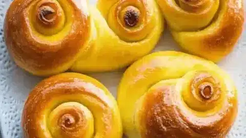 Freshly baked St. Lucia saffron buns, golden and aromatic, on a wooden table.