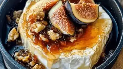 Creamy baked brie topped with fig jam served on a wooden board