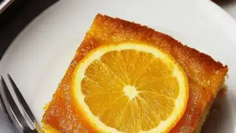 Delicious slice of Greek Orange Cake on a plate with a garnish of orange slices.