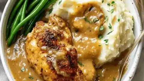 Delicious chicken and garlic gravy with cheesy mashed potatoes on a plate.