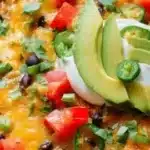 Cheesy quinoa and black bean taco skillet topped with fresh ingredients.
