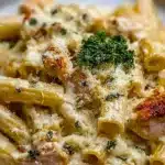 Creamy Chicken Rigatoni Alfredo pasta topped with parsley on a white plate.