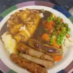 Plate of classic British beef sausages with mashed potatoes and onion gravy