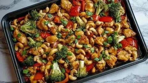 Sheet pan cashew chicken with vibrant vegetables and savory sauce.