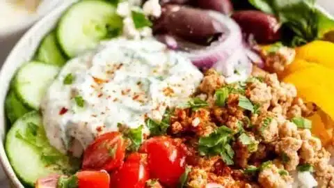 Delicious Greek Turkey Rice Bowls garnished with fresh vegetables and herbs.