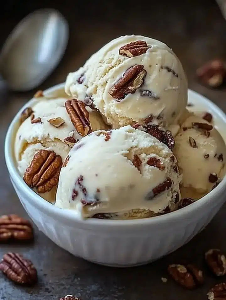 Bowl of homemade butter pecan ice cream topped with pecans