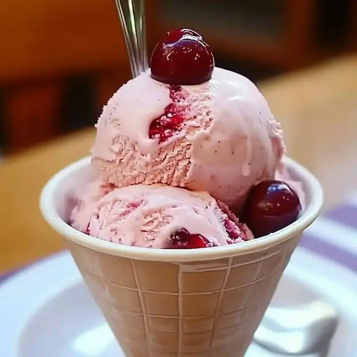 Scoop of homemade cherry vanilla ice cream in a bowl with cherries on top