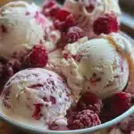 Delicious homemade raspberry ripple ice cream in a bowl with fresh raspberries.