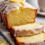 Delicious slice of lemon loaf bread on a wooden table with lemon slices