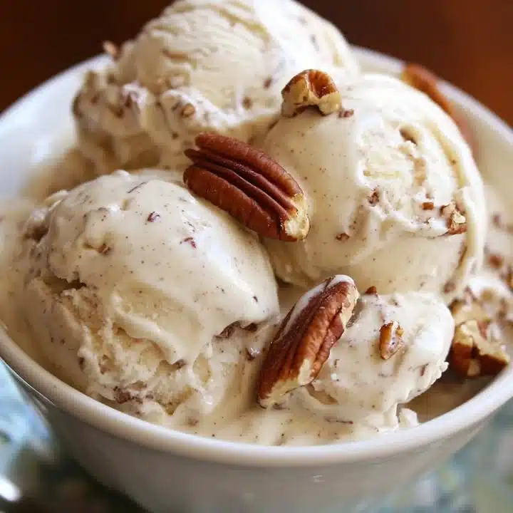 Delicious Pecan Apple Cinnamon Ice Cream in a bowl, garnished with cinnamon sticks.