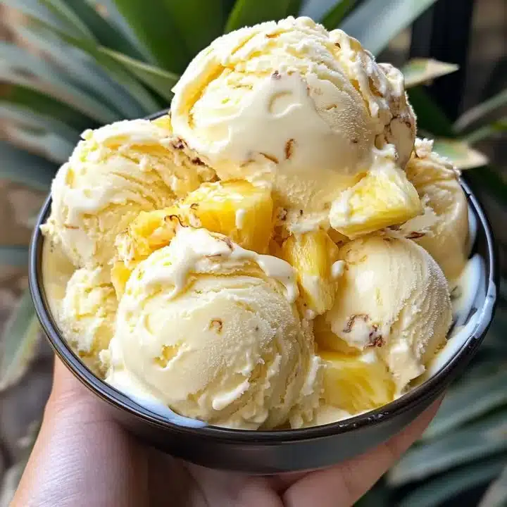 Delicious homemade pineapple ice cream in a bowl with fresh pineapple slices