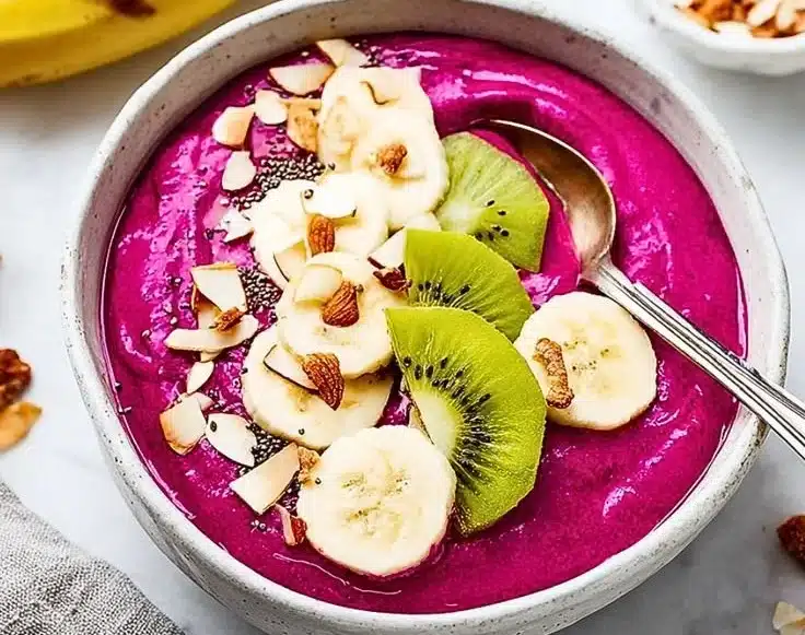 Colorful pitaya smoothie bowl topped with fresh fruits and granola