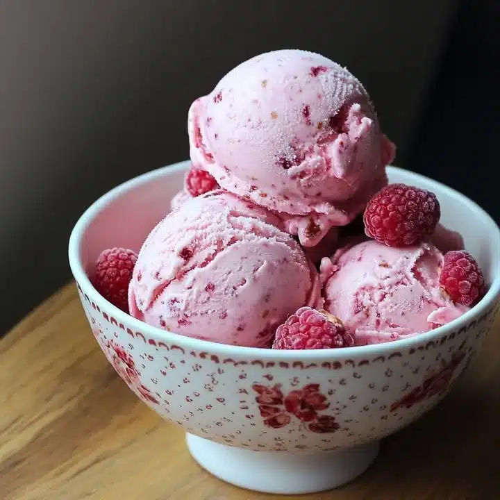 Delicious raspberry hazelnut ice cream served in a bowl with fresh raspberries and hazelnuts