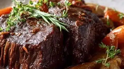 Delicious Red Wine Pot Roast served with vegetables on a rustic plate.