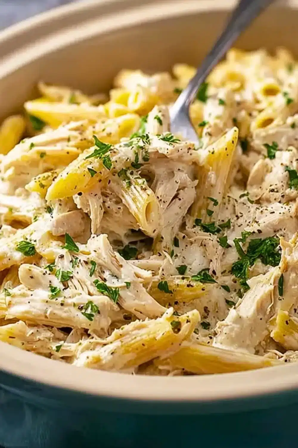 Creamy slow cooker chicken alfredo served with pasta and garnished with parsley