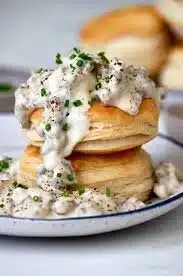 A plate of fluffy biscuits topped with creamy sausage gravy.