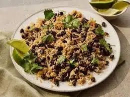 A delicious plate of black beans and rice served with fresh herbs and spices.