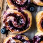 Freshly baked blueberry cinnamon rolls topped with icing and blueberries