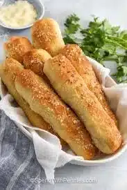 Freshly baked golden-brown breadsticks served with marinara sauce.