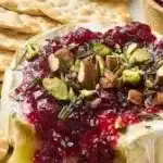 Delicious Brie appetizer served with fruit and nuts on a wooden platter
