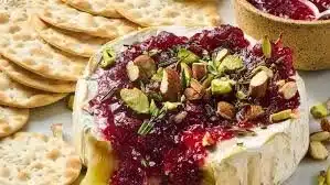 Delicious Brie appetizer served with fruit and nuts on a wooden platter
