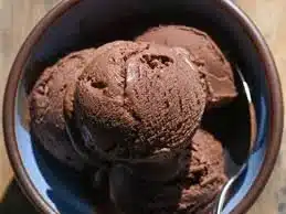 Bowl of creamy homemade chocolate ice cream topped with chocolate shavings.