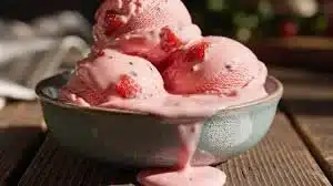 Bowl of homemade strawberry ice cream topped with fresh strawberries