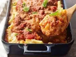 Delicious baked ziti topped with melted cheese and fresh herbs in a serving dish.