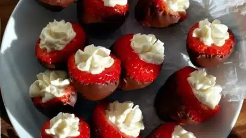 Chocolate covered cheesecake strawberries on a white plate