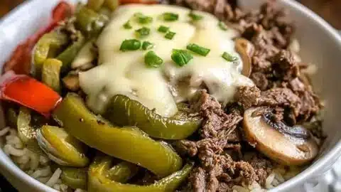 A delicious Philly Cheesesteak Bowl topped with cheese and peppers.