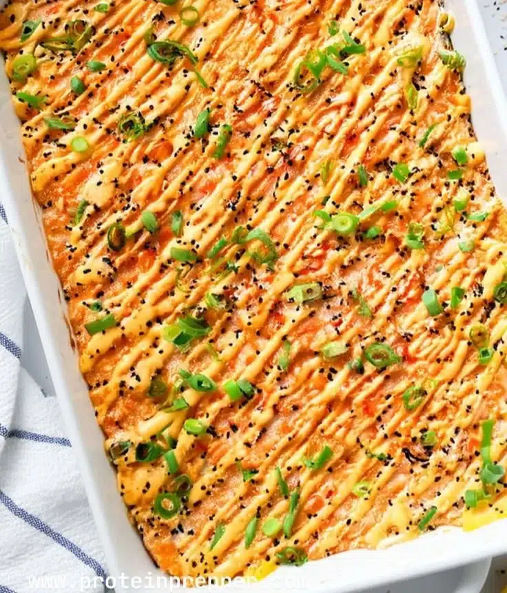 Delicious salmon sushi bake topped with creamy sauce and herbs