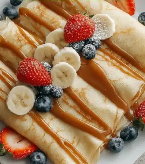 Fluffy egg white crepes stacked and served with fresh fruits and syrup.