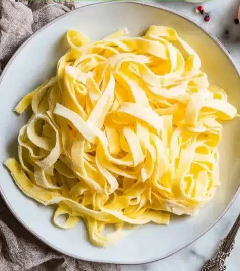 Bowl of homemade keto egg noodles served with sauce and herbs