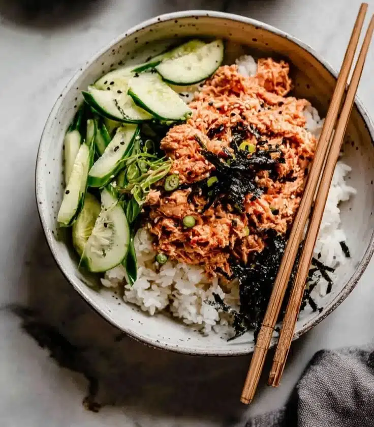 Spicy tuna rice bowl topped with fresh vegetables and sesame seeds