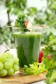 Freshly made green juice in a glass with vibrant green ingredients.