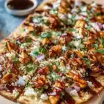 Savory BBQ chicken flatbread topped with cheese and fresh vegetables