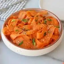 Colorful carrot ribbon salad served in a bowl with fresh herbs.