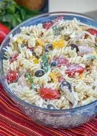 Delicious cold pasta salad topped with vibrant vegetables and Italian dressing