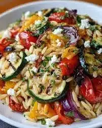Creamy orzo with roasted vegetables in a bowl, garnished with herbs.