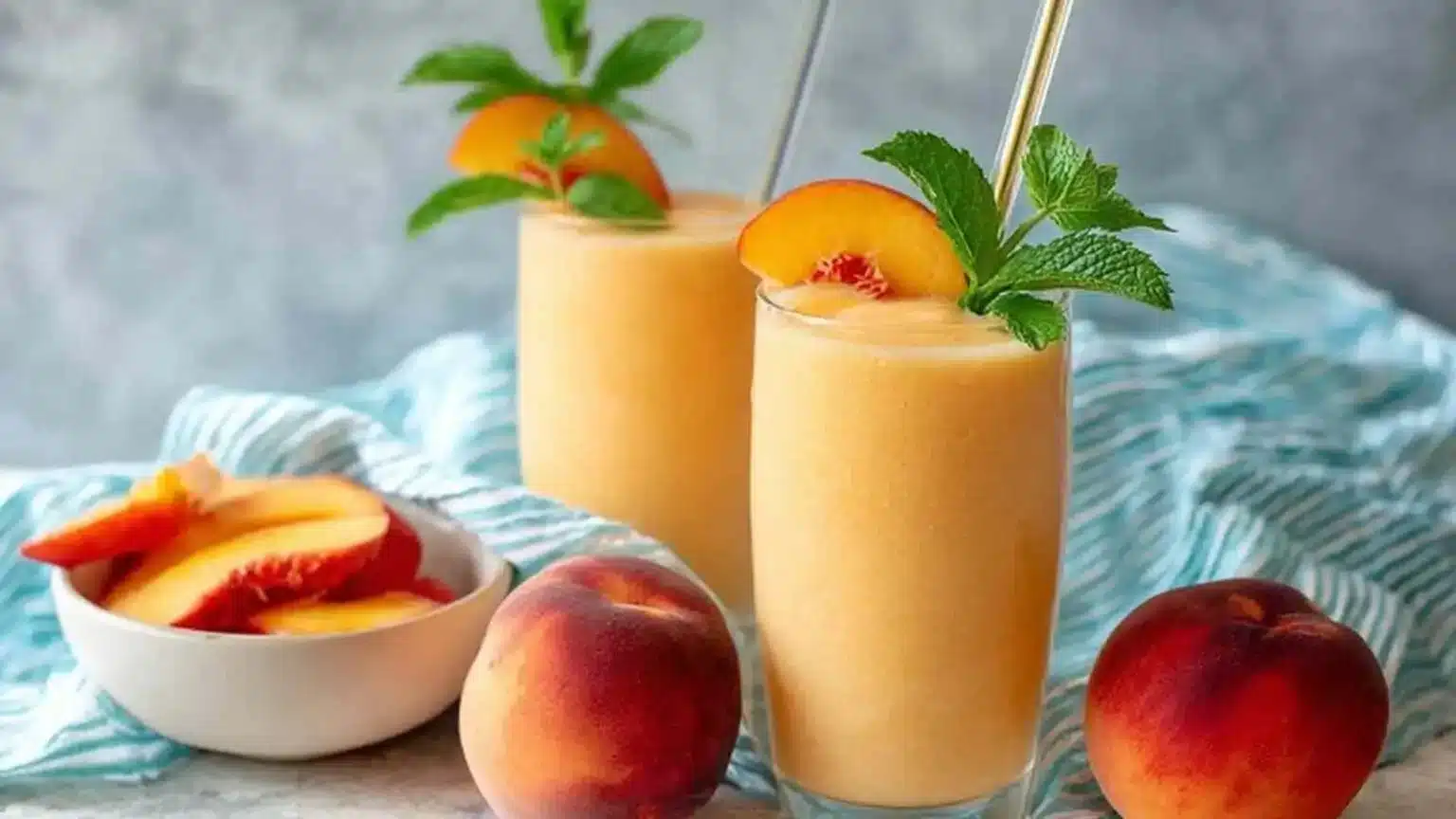 High protein peach smoothie in a glass with fresh peach slices