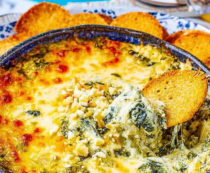 Creamy hot spinach artichoke dip served in a bowl with tortilla chips