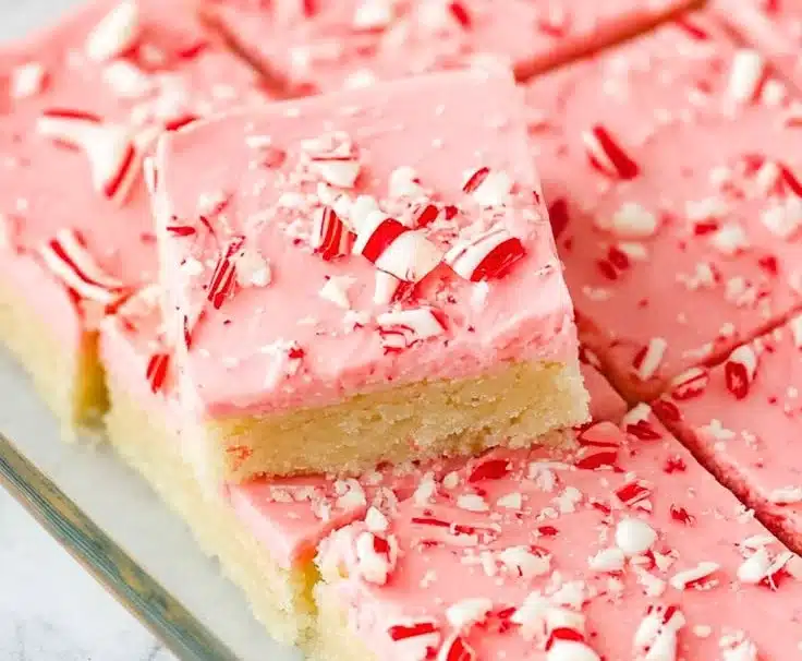 Festively decorated peppermint sugar cookie bars on a baking tray.