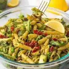 Colorful pesto pasta salad with fresh vegetables and herbs.